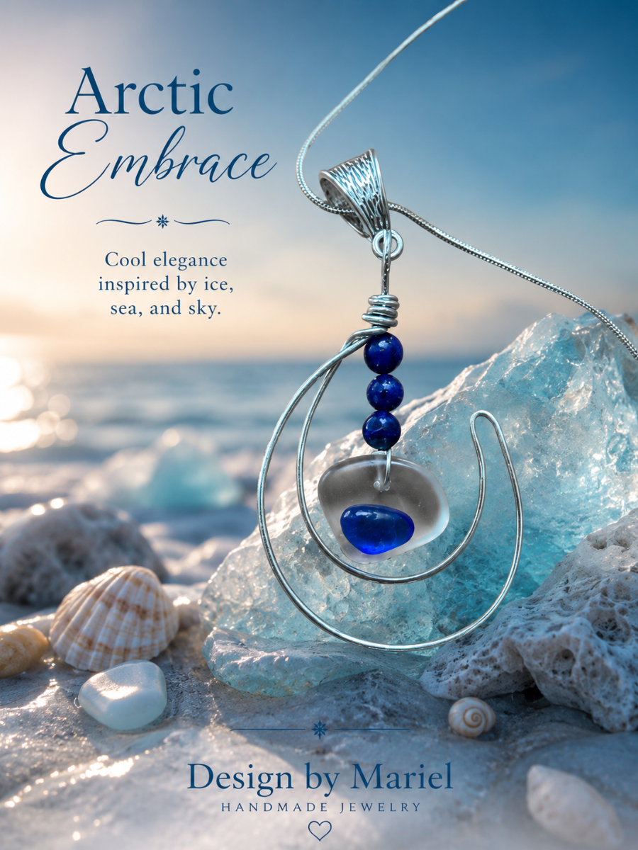 A handmade silver crescent moon pendant necklace with a blue heart-shaped stone and three dark blue beads, displayed on a beach with ice, shells, and ocean water in the background. Text on the image reads 'Arctic Embrace' and 'Design by Mariel Handmade Jewelry'.