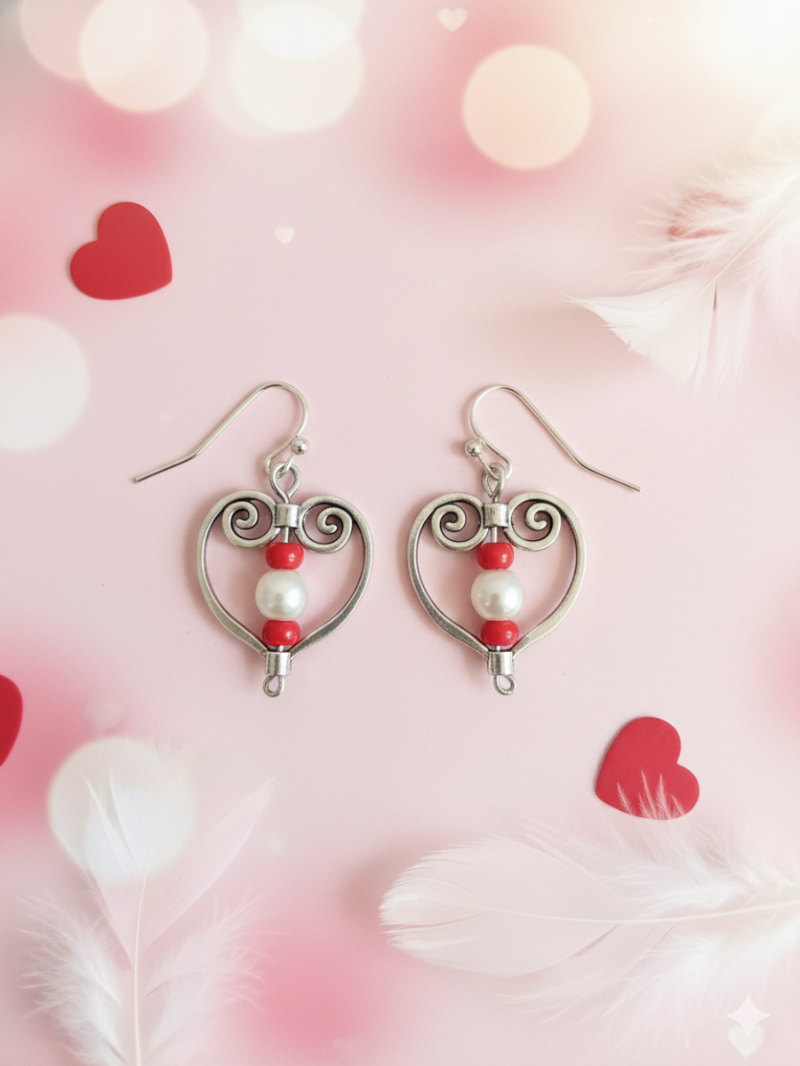 Heart-shaped earrings with pearls and red beads on a pink background with heart shapes.