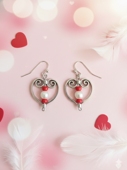Heart-shaped earrings with pearls and red beads on a pink background with heart shapes.