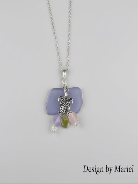 Necklace with turtle charm and sea glass pendant on a wooden surface